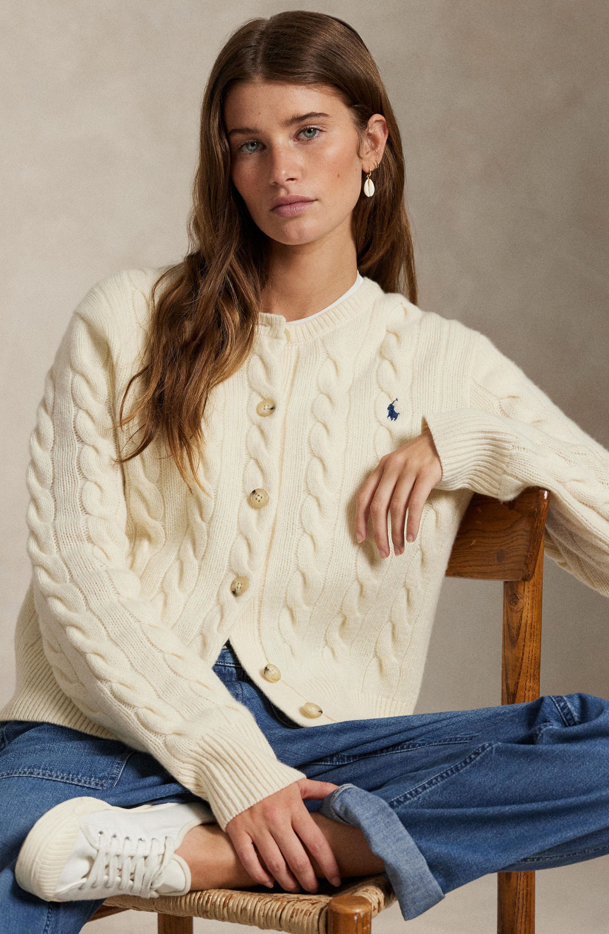 A woman wearing a white knit cardigan.