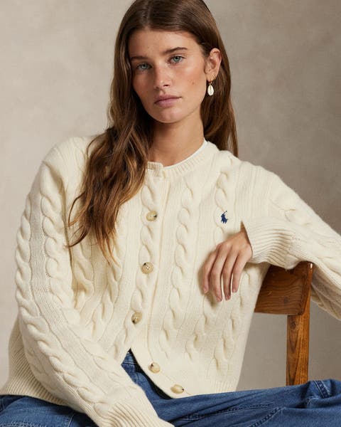 A woman wearing a white knit cardigan.