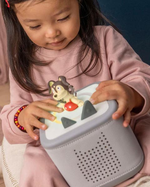 A girl playing a Toniebox audio player.