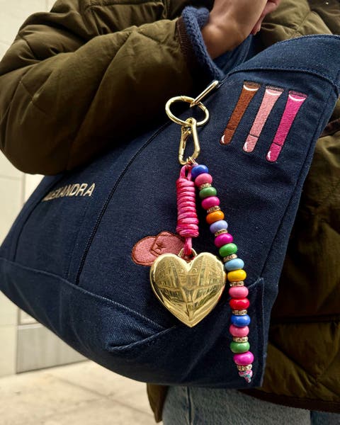 An embroidered bag with bag charms.