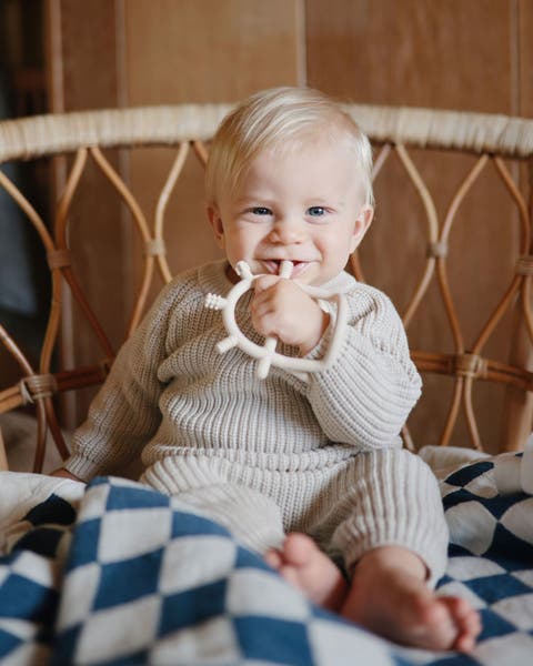 A baby holding a teething toy.