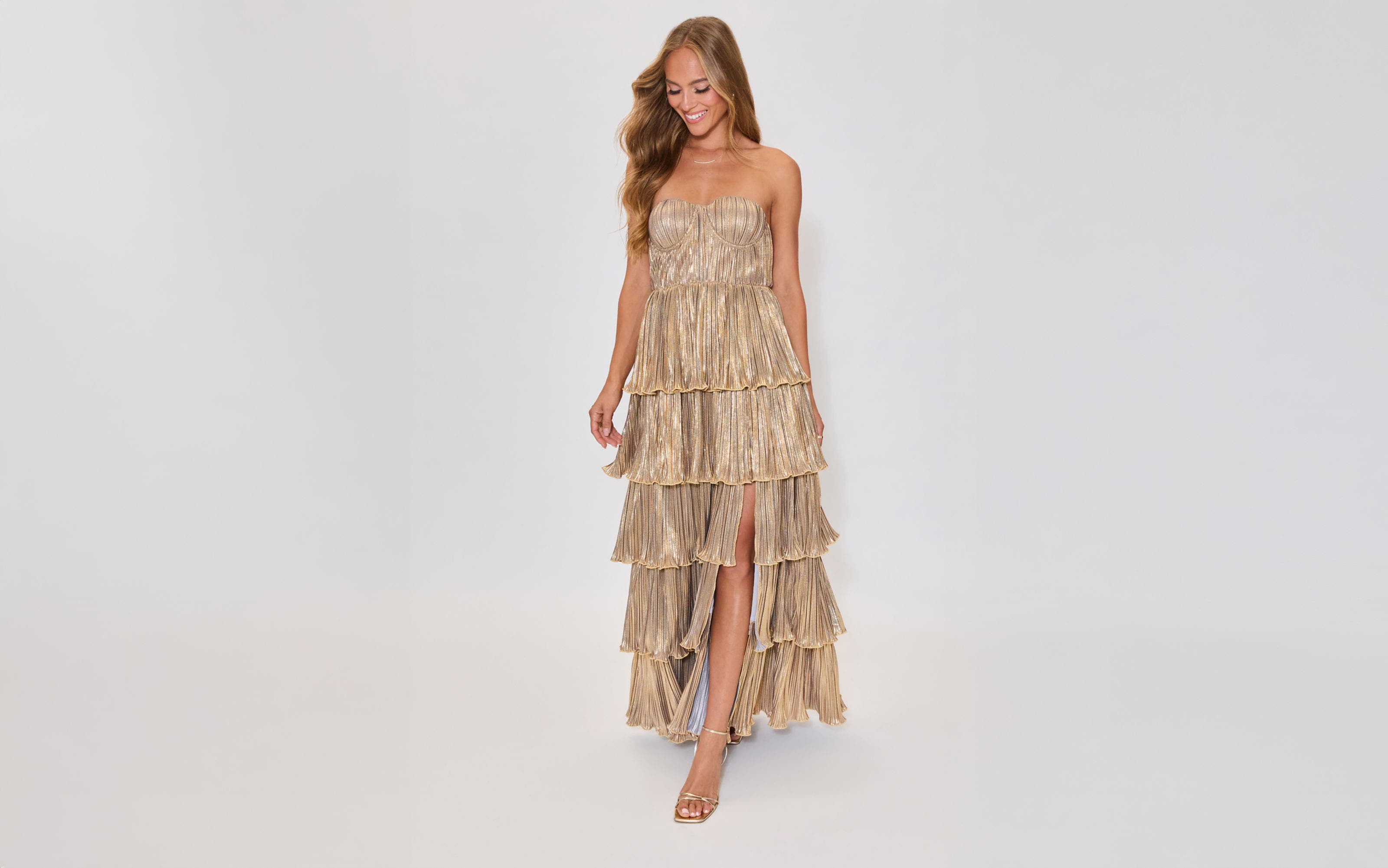 A woman wearing a shimmery gold tiered strapless dress.