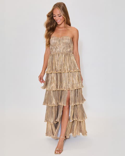 A woman wearing a shimmery gold tiered strapless dress.