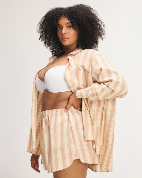 Woman wearing yellow striped matching short and long sleeve top pajamas. 