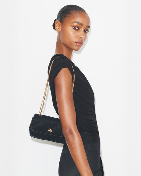 A woman wearing a black quilted crossbody bag.