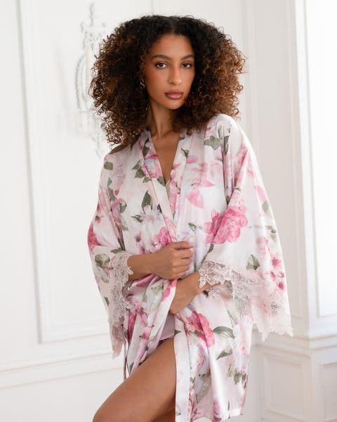 Woman wearing white and pink floral short silky robe. 