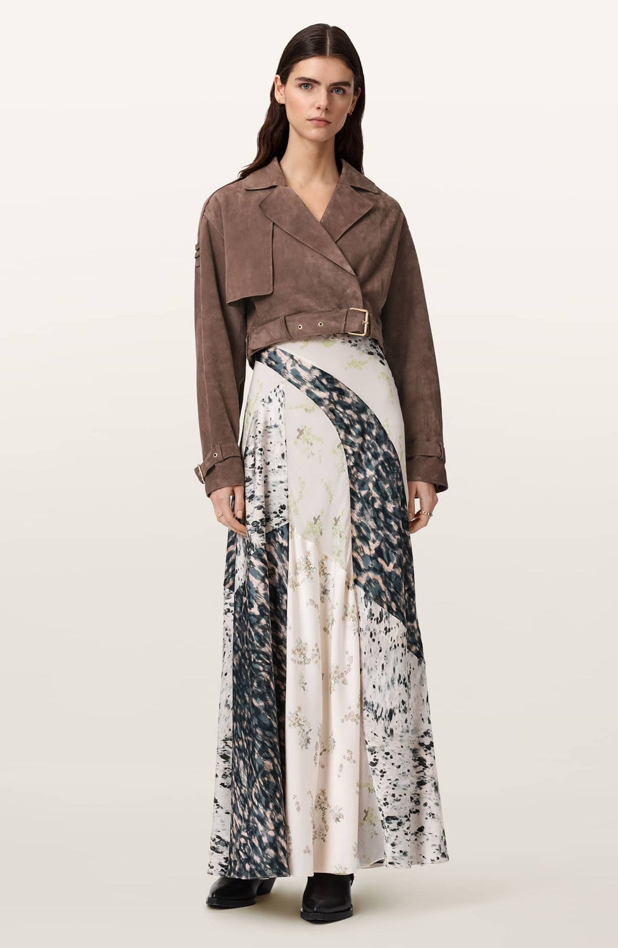 A woman in light brown cropped suede jacket over a satin slip dress.