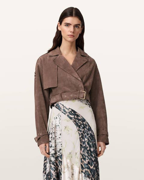 A woman in light brown cropped suede jacket over a satin slip dress.