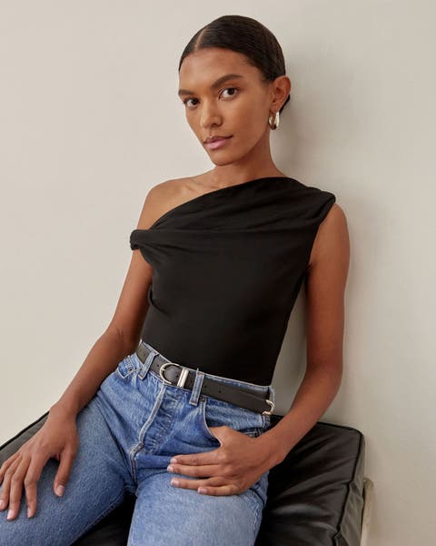 A woman wearing a black off-the-shoulder top and a pair of jeans.