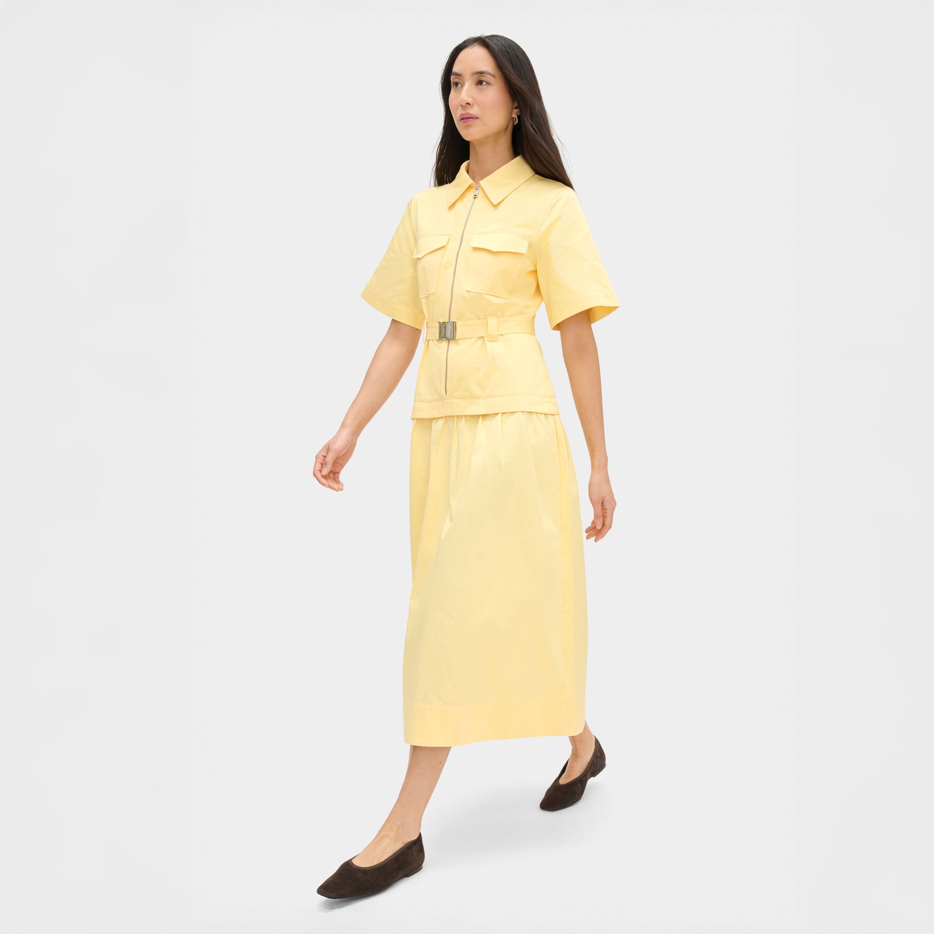 A woman wearing a matching yellow top and midi skirt.