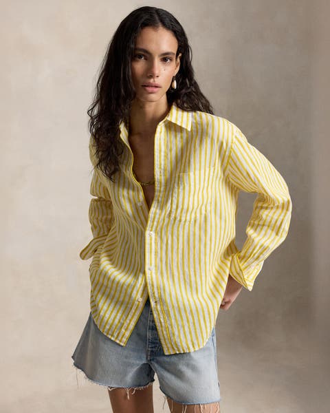 A woman wearing a yellow striped polo and denim shorts.