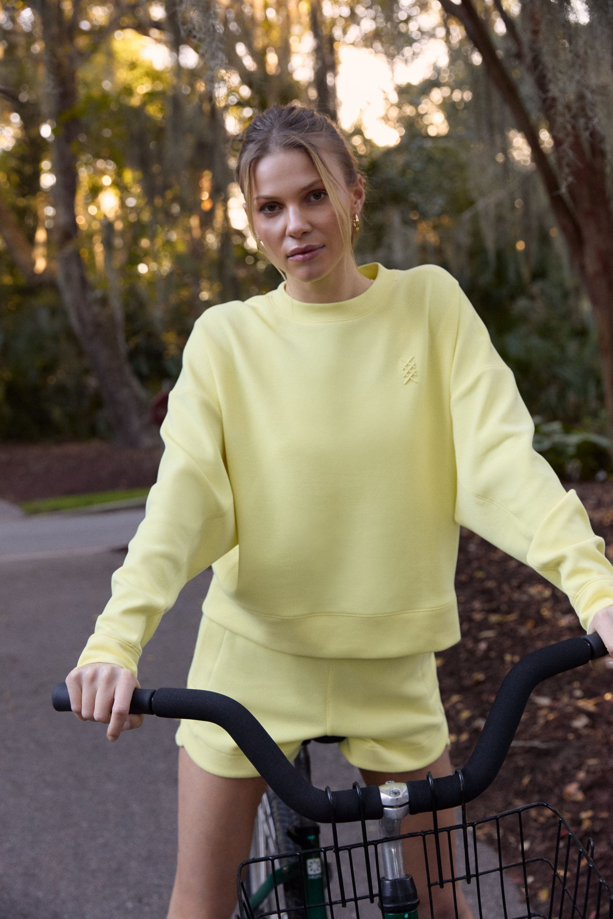 A woman wearing a matching yellow active sweatshirt and shorts.