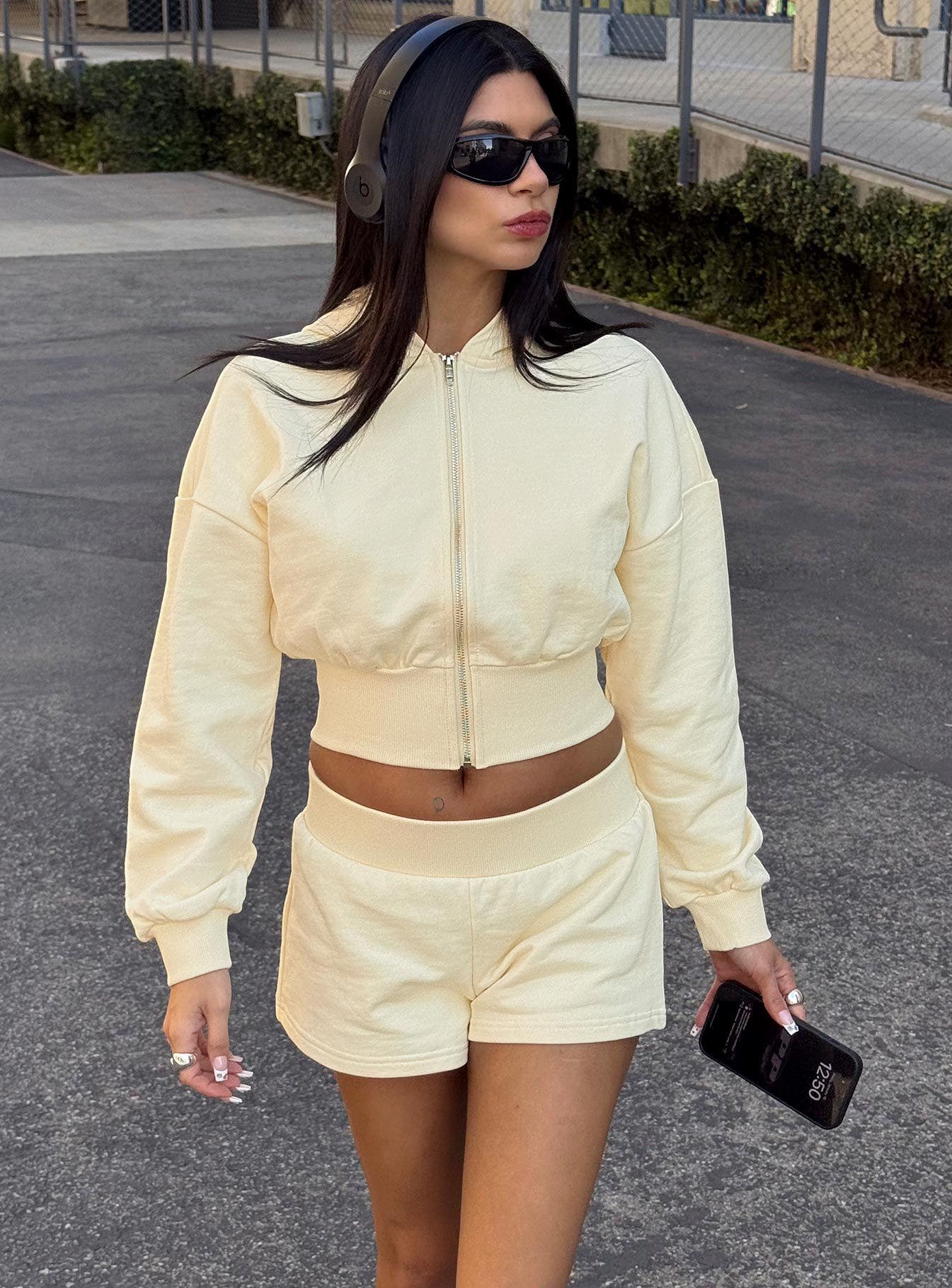 A woman wearing a cropped, yellow sweatshirt and matching shorts.