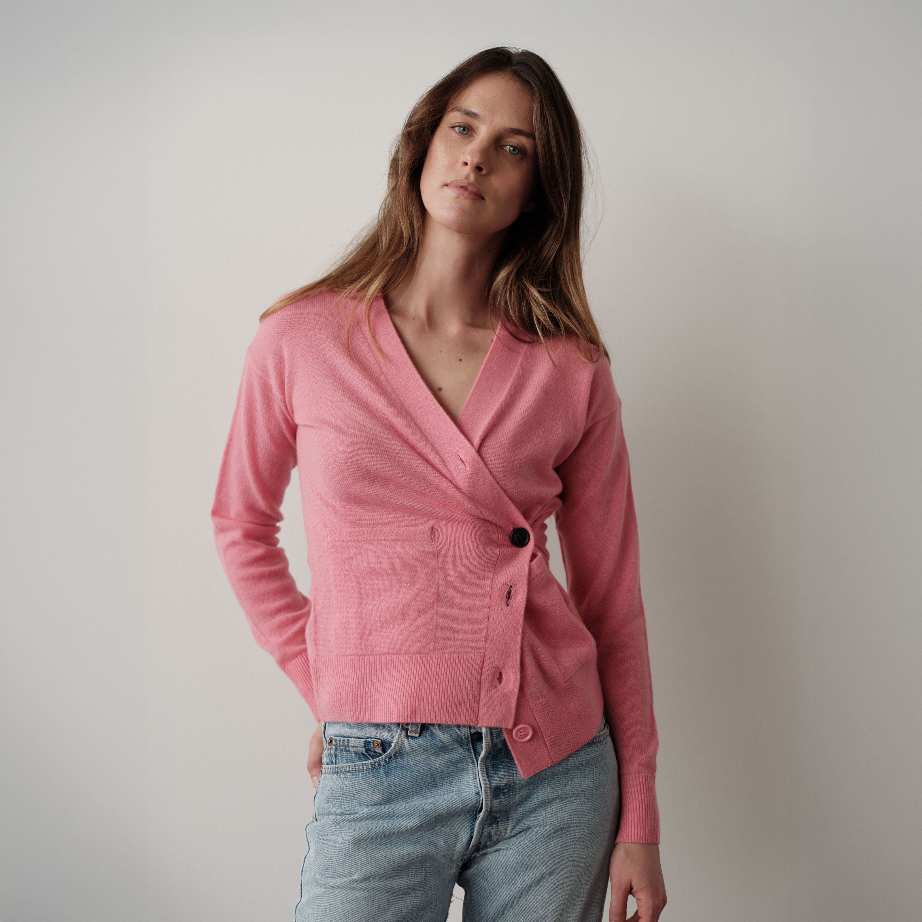 A woman wearing a pink sweater and a pair of jeans.