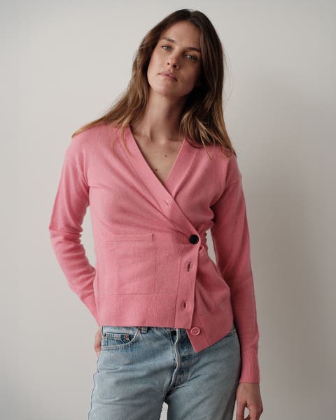 A woman wearing a pink sweater and a pair of jeans.