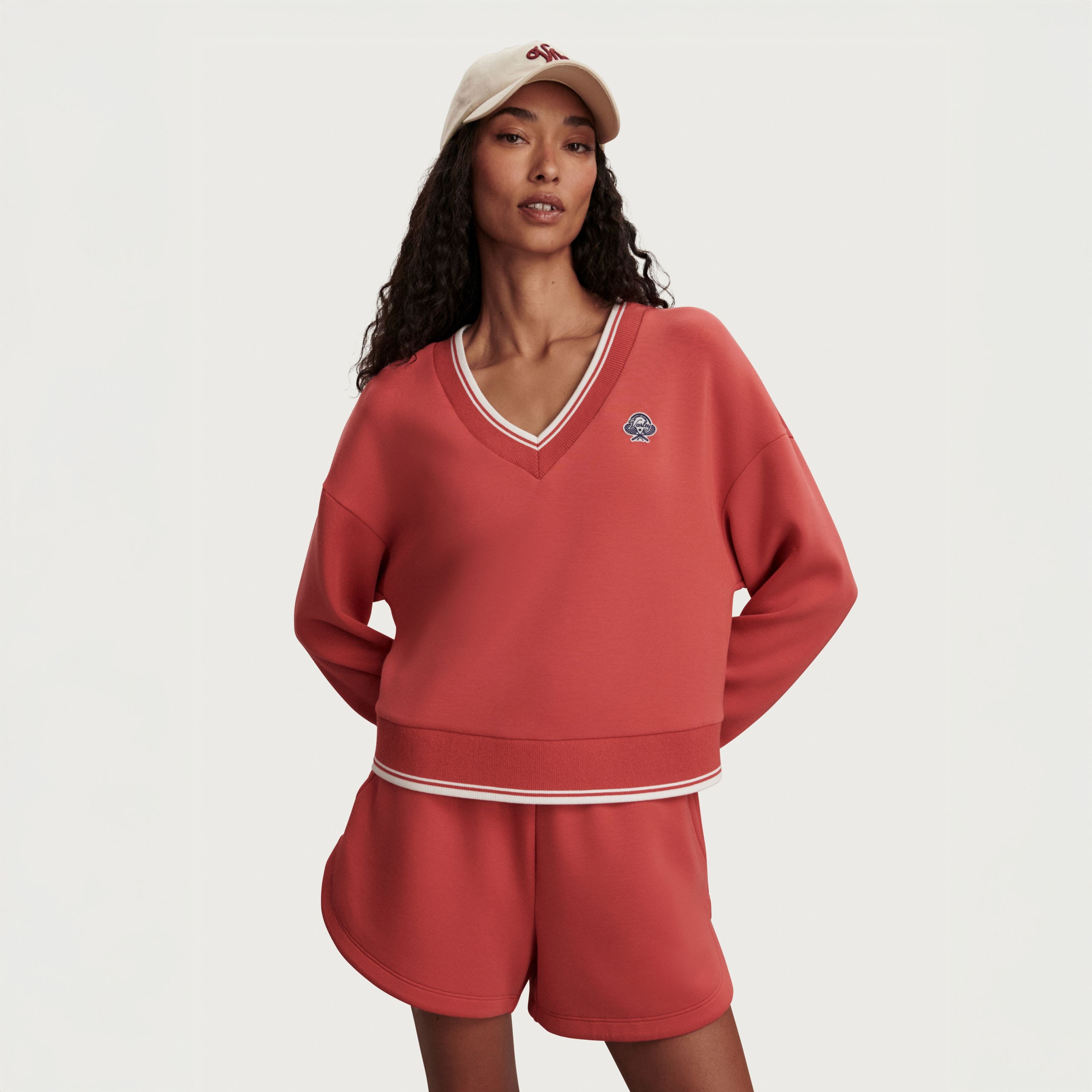 A woman wearing an orange matching sweatshirt and shorts.