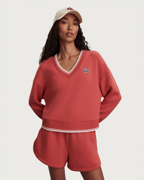 A woman wearing an orange matching sweatshirt and shorts.
