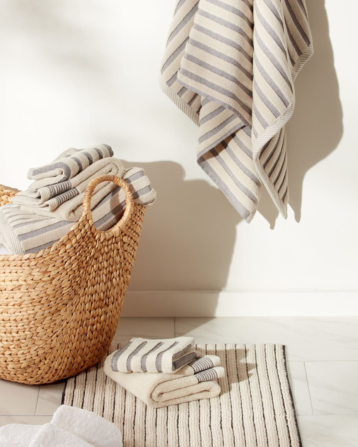 A set of striped towels and a bathmat in neutrals.