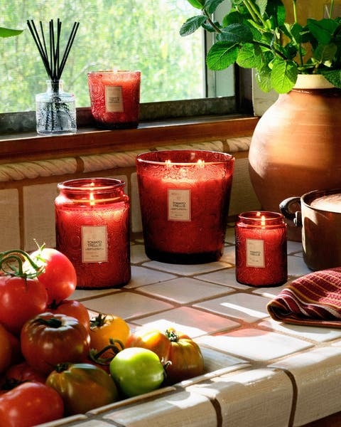 A collection of Voluspa candles on a tile countertop.