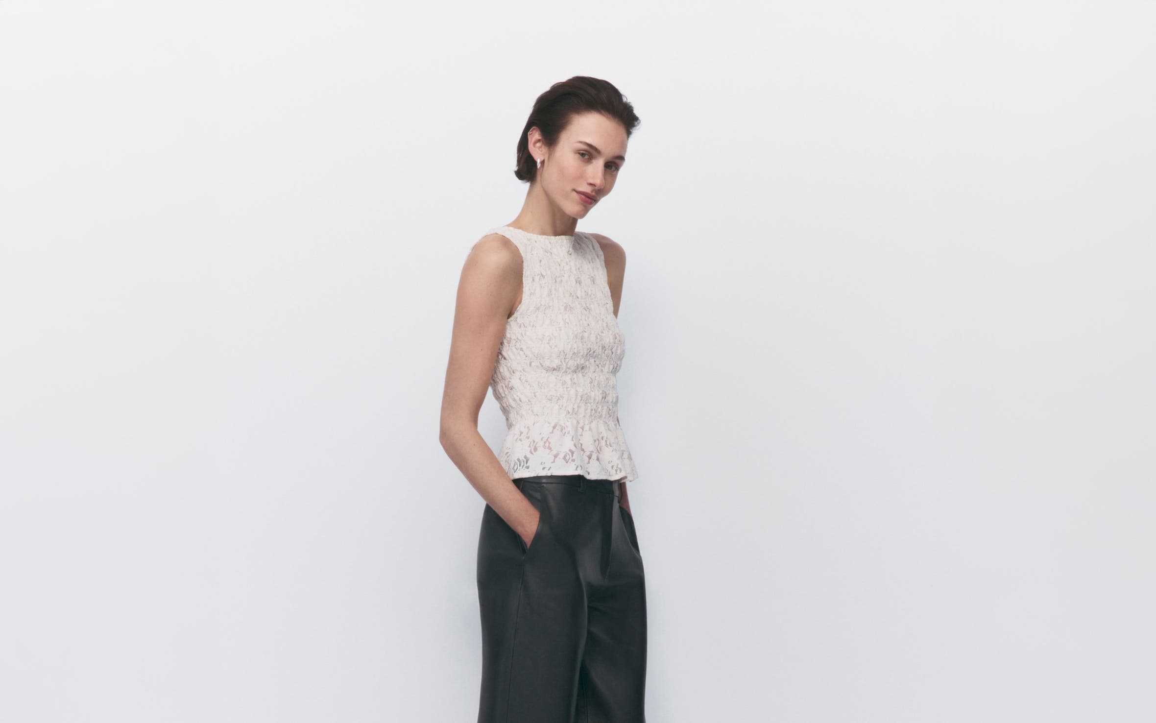 A woman in black wide-leg pants and a sleeveless lace top.
