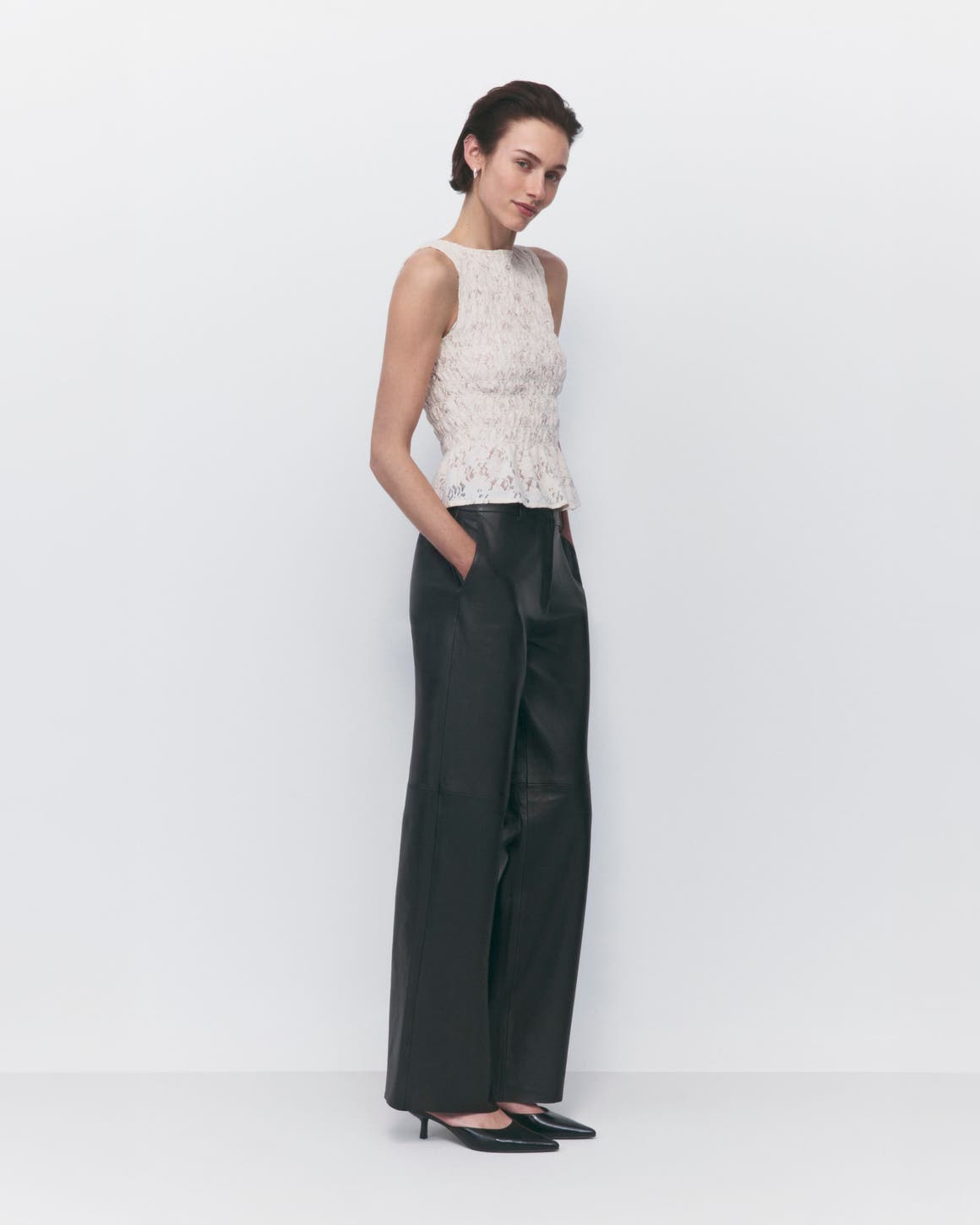 A woman in black wide-leg pants and a sleeveless lace top.