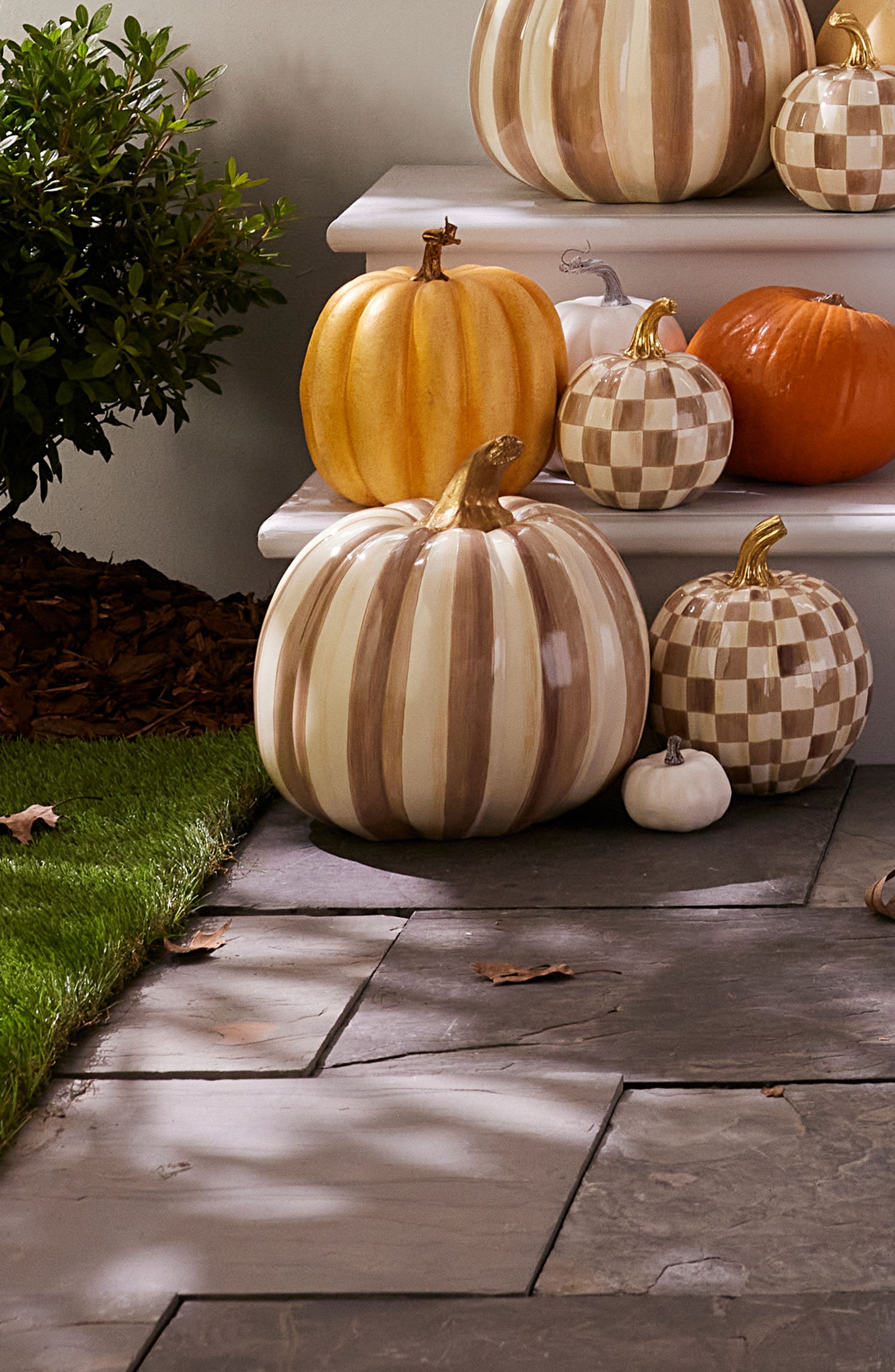 Ceramic pumpkins in checks and stripes on a front porch. 