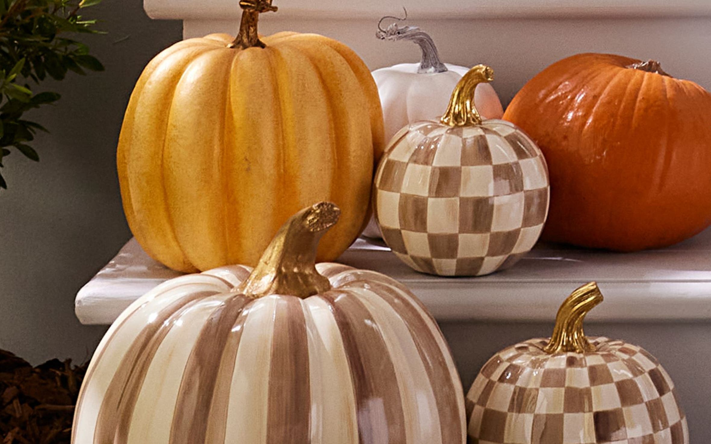 Ceramic pumpkins in checks and stripes on a front porch.