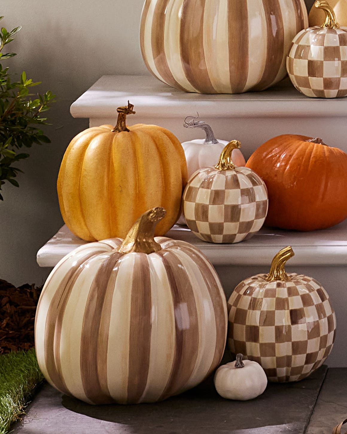 Ceramic pumpkins in checks and stripes on a front porch.