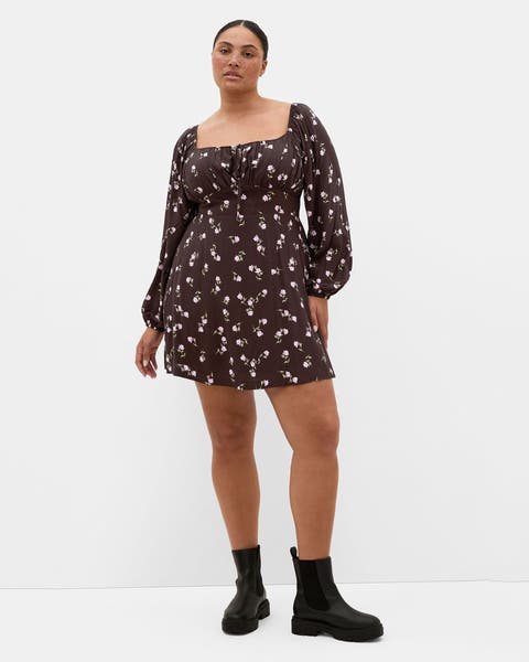 A woman in a short brown long sleeve floral dress.