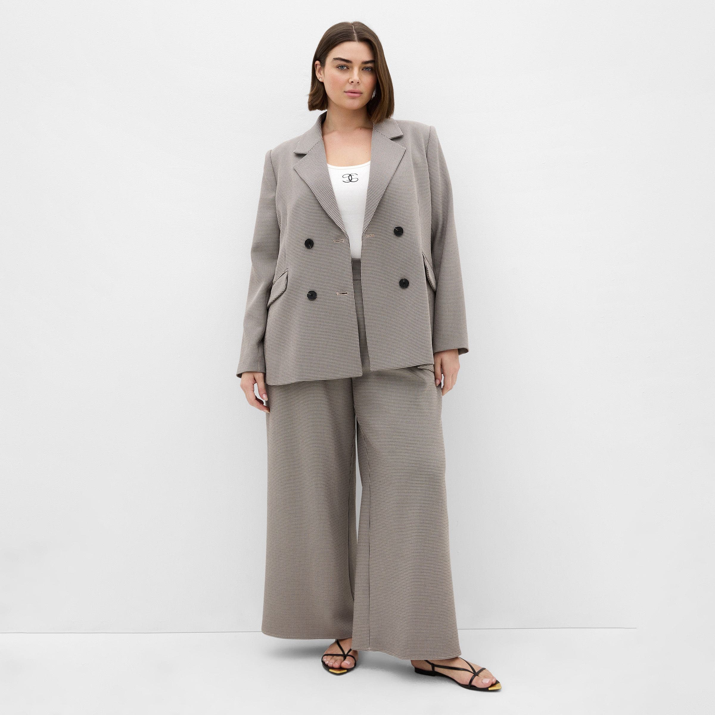 A woman in a tan double-breasted blazer and matching pants.