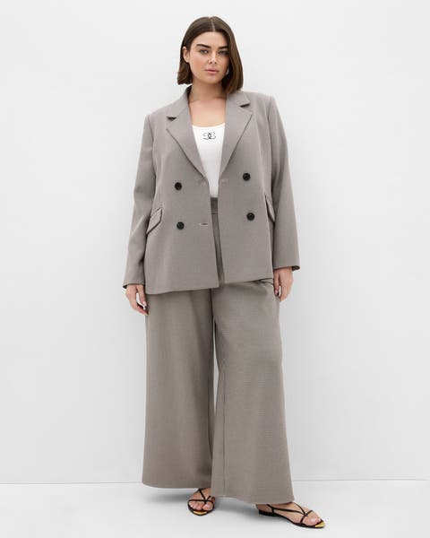A woman in a tan double-breasted blazer and matching pants.