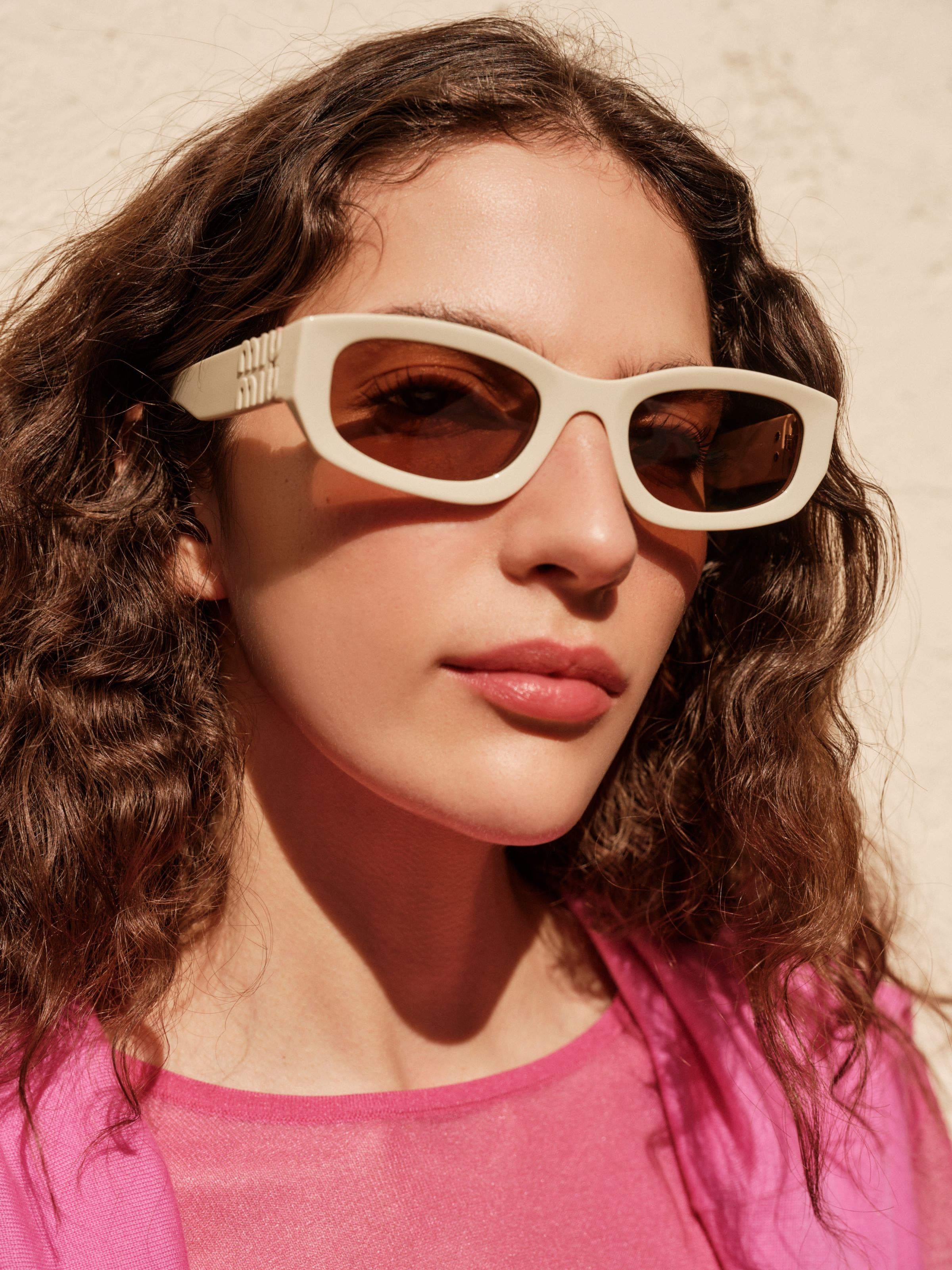 A woman wearing a pair of cream sunglasses. 