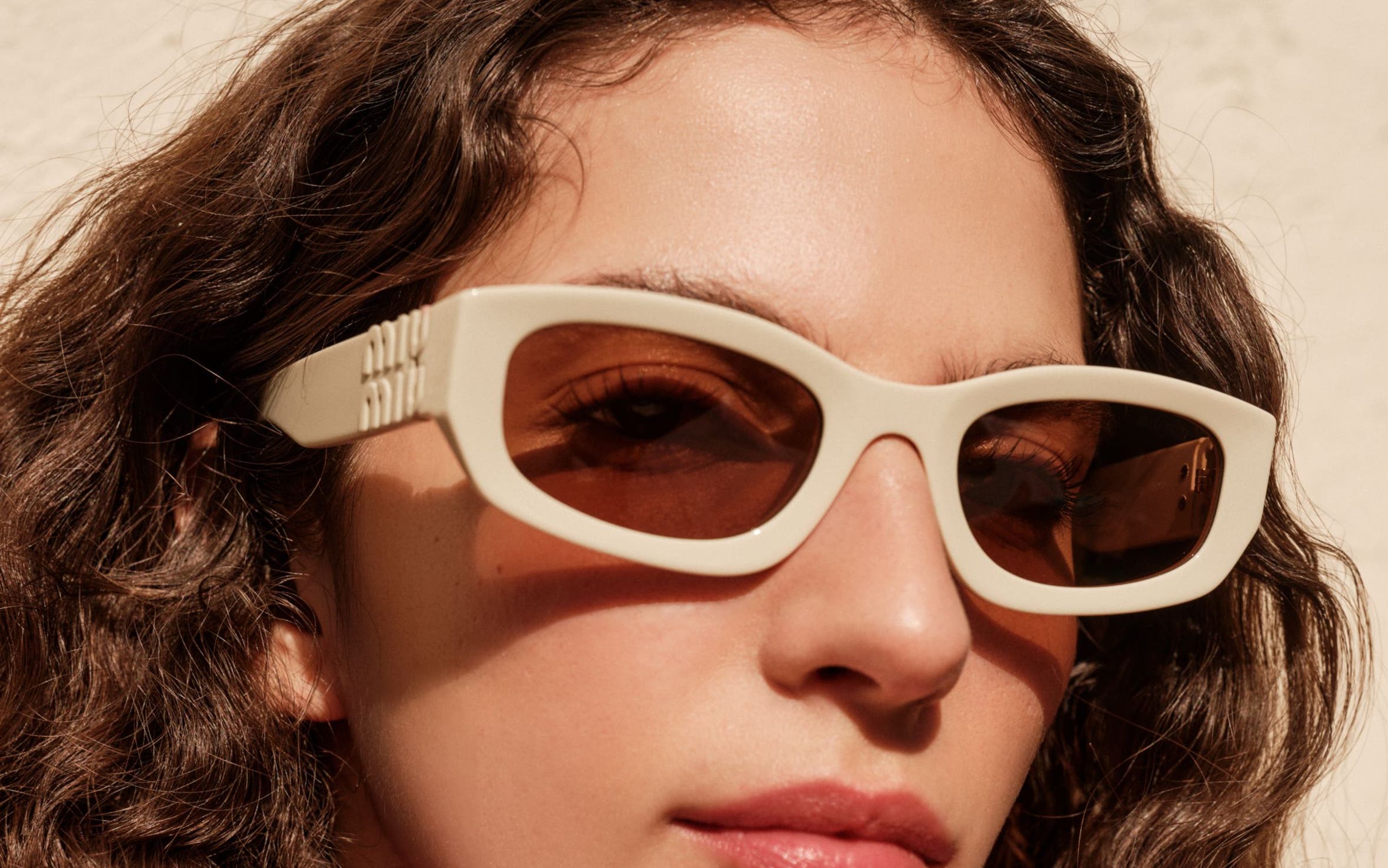 A woman wearing a pair of cream sunglasses.