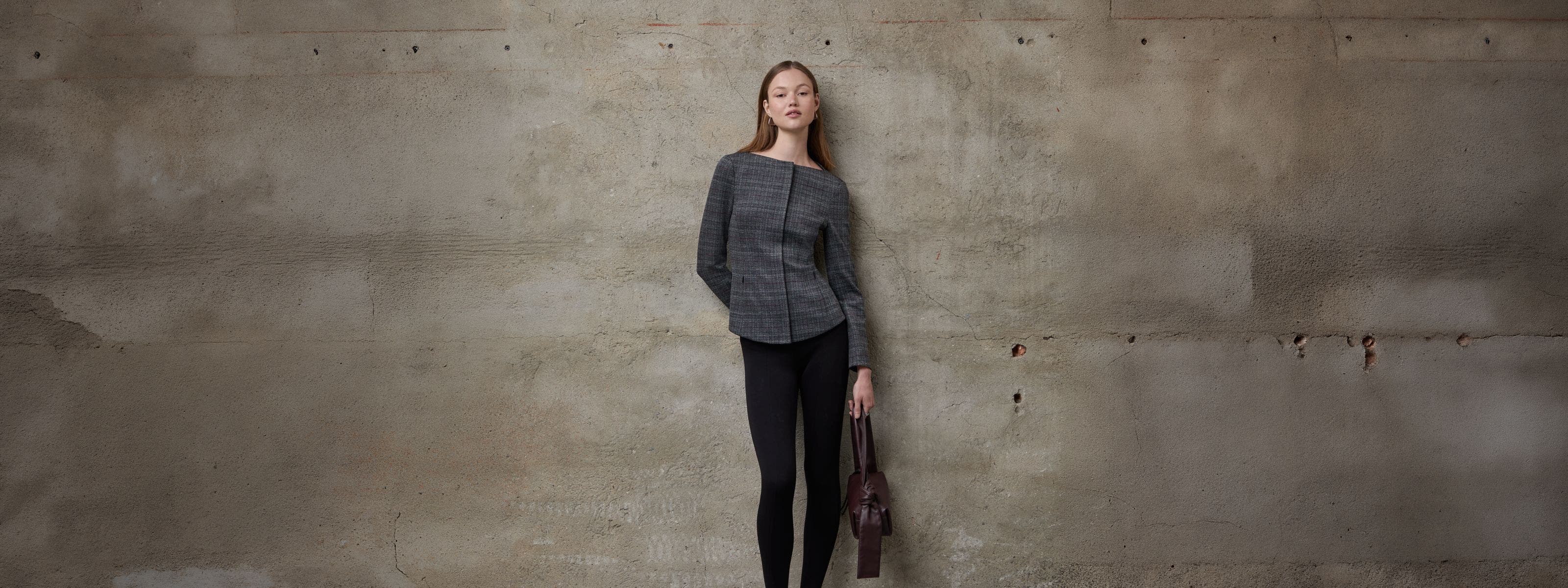 A woman wearing a tailored jacket and black pants.