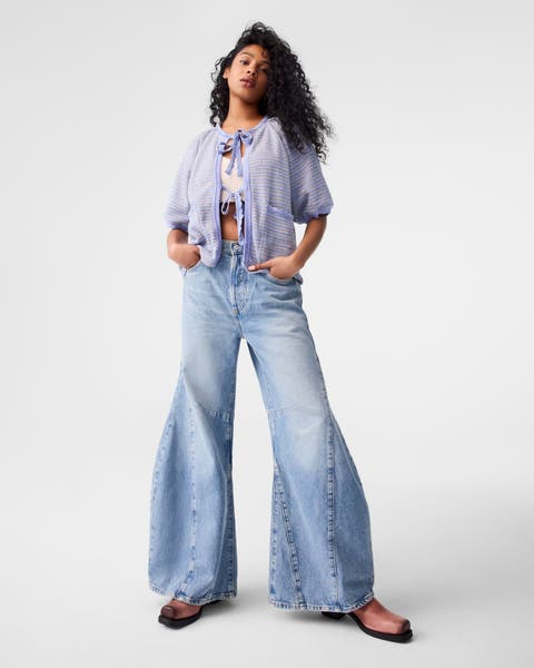 A woman wearing barrel jeans with a lavender cardigan and brown boots.