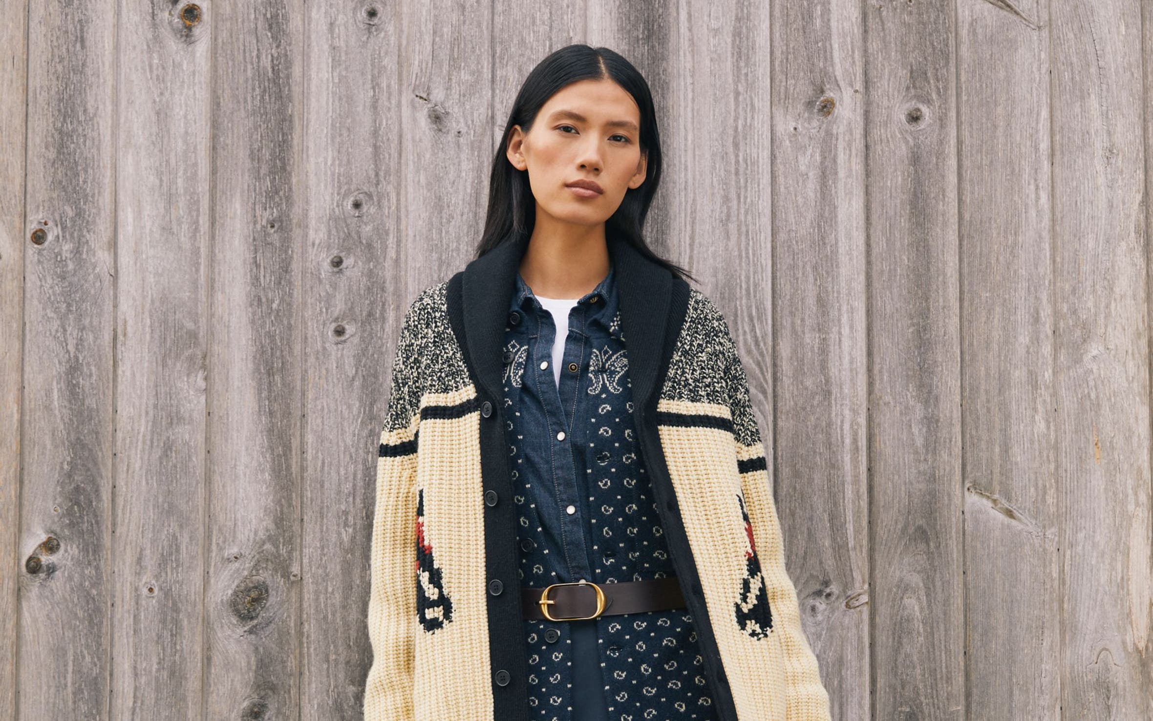 A woman wearing an oversized cardigan and denim skirt.