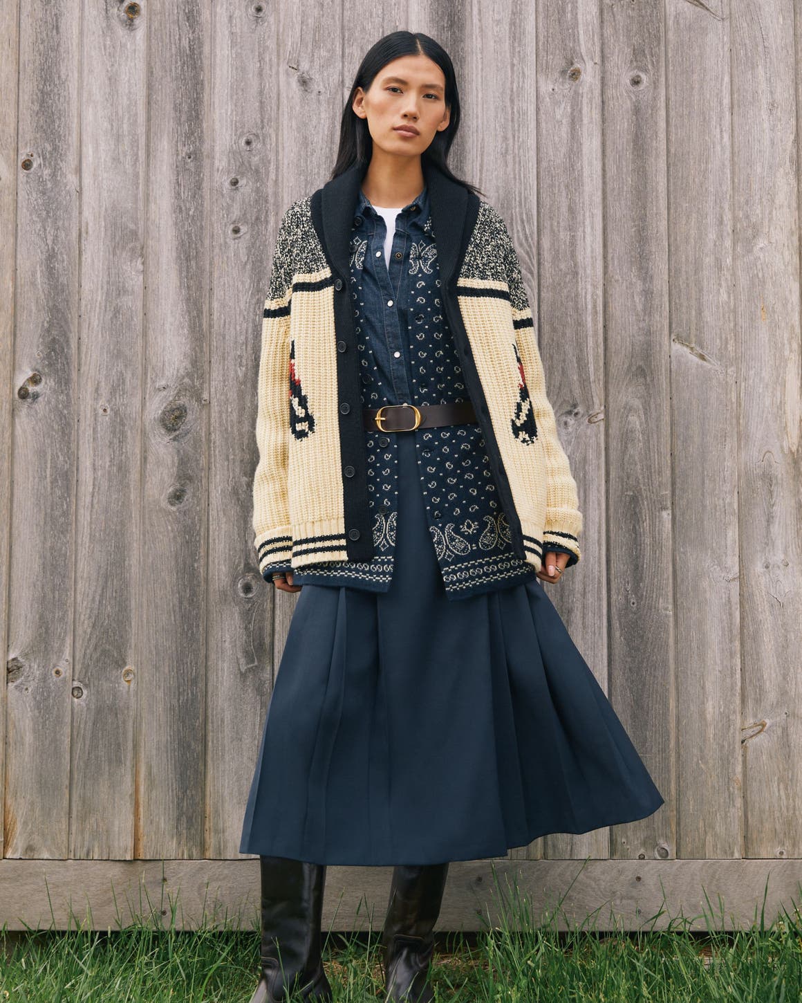 A woman wearing an oversized cardigan and denim skirt.