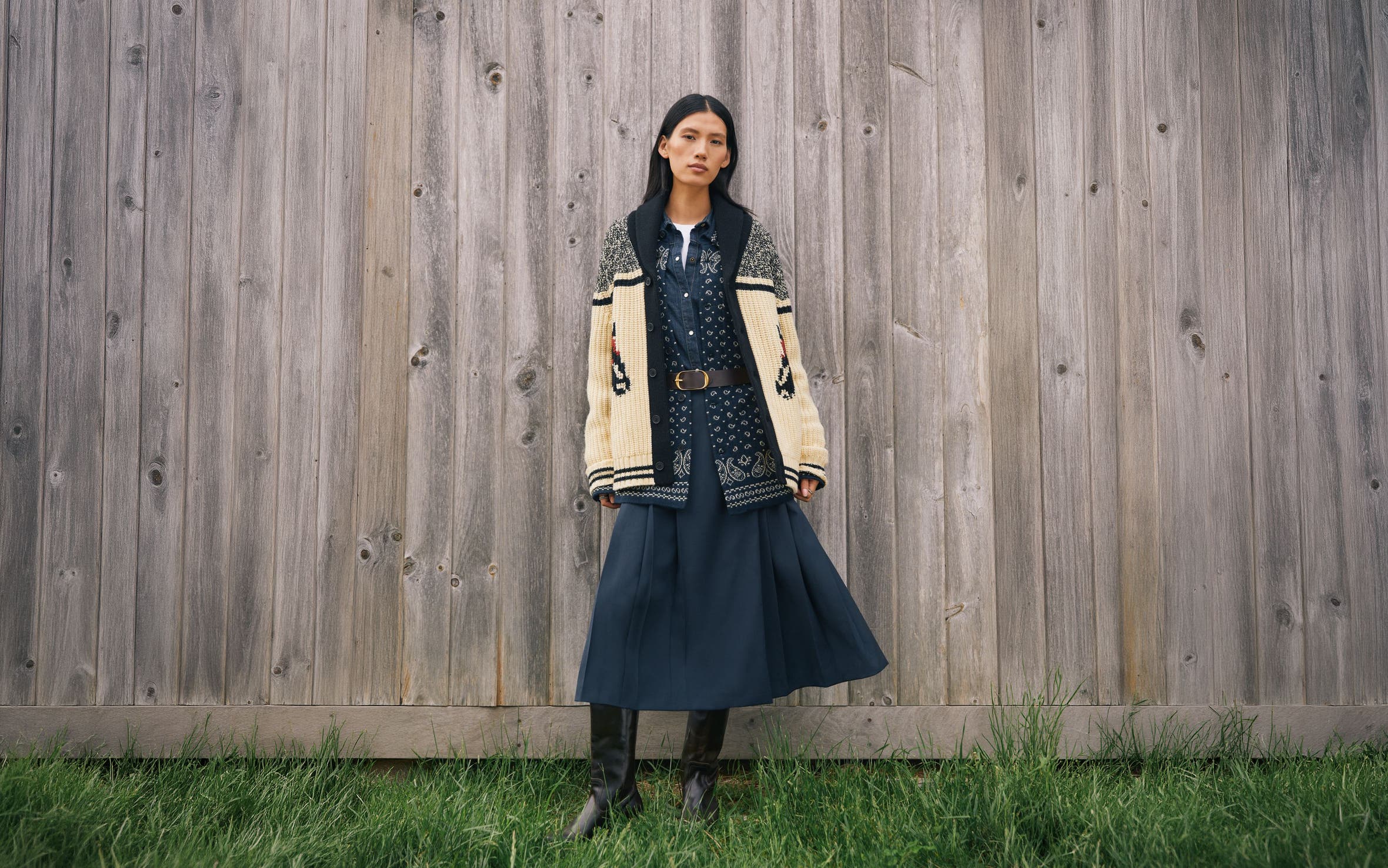 A woman wearing a chunky cardigan and long skirt.