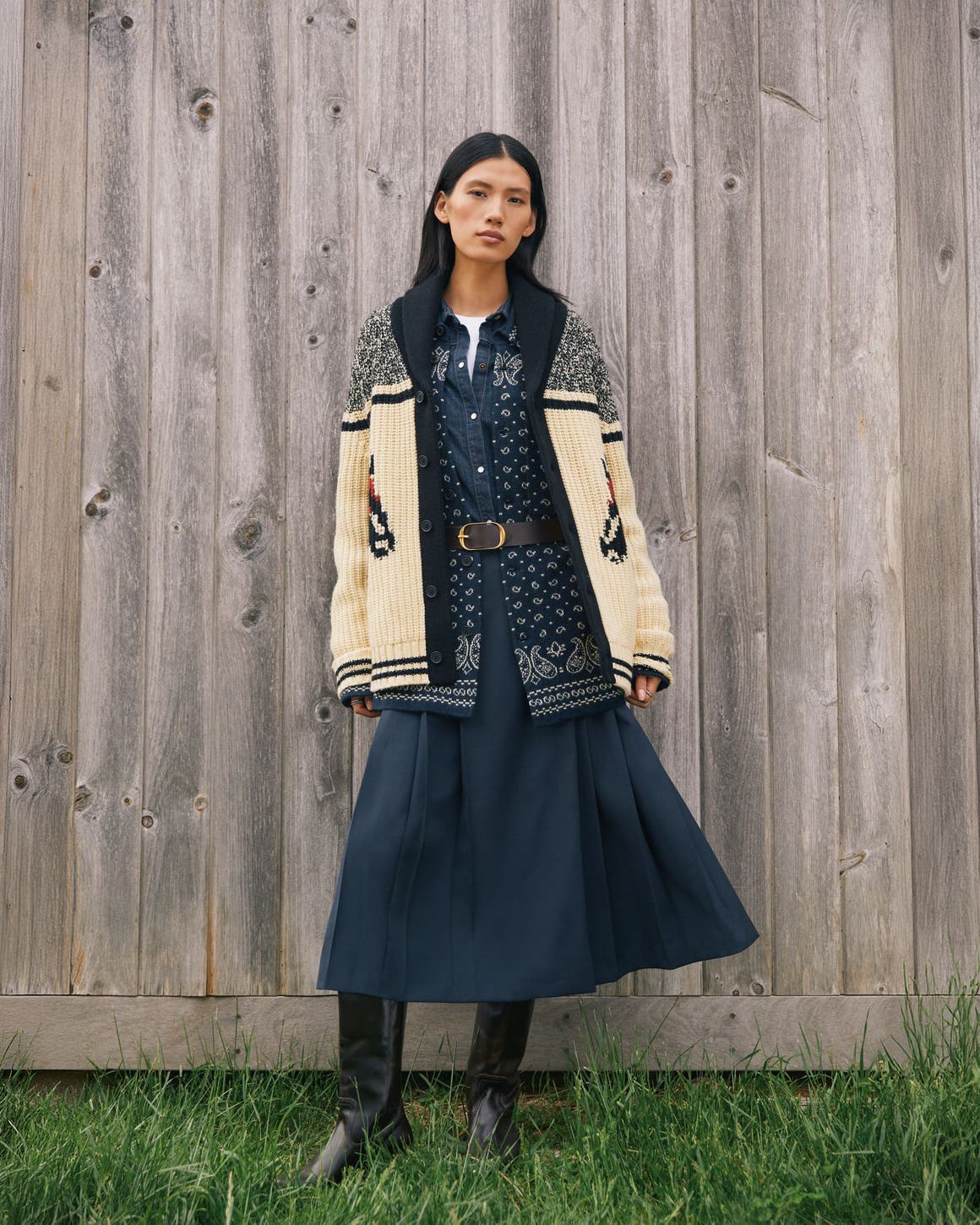A woman wearing a chunky cardigan and long skirt.