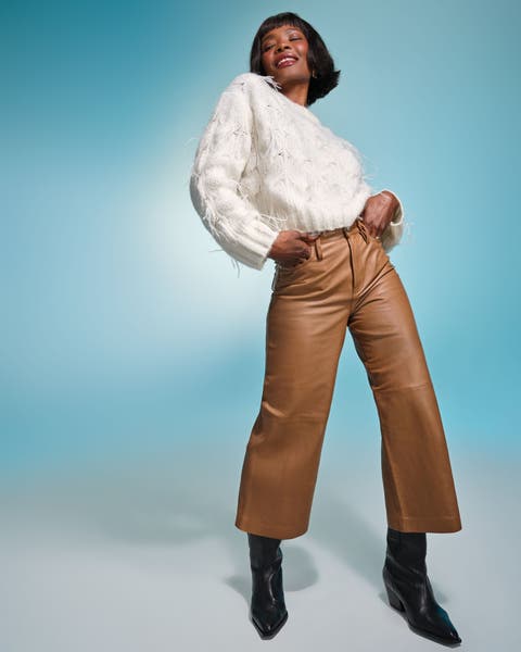 Model wearing a white sweater with tan wide-leg leather pants and black boots.