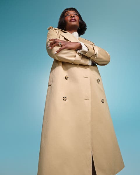 A woman wearing a long khaki trench coat.
