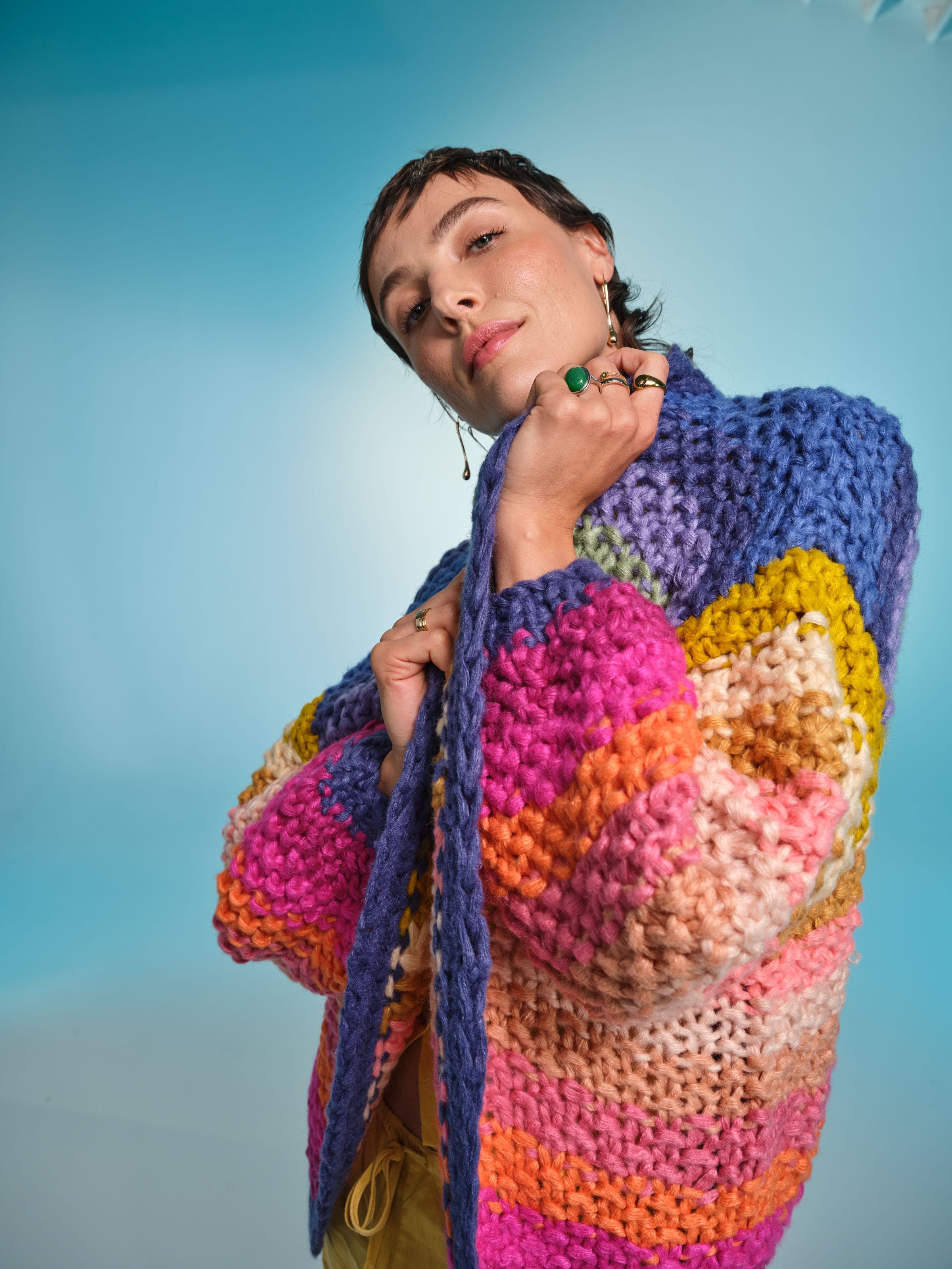 Woman wearing a chunky, multicolored hand-knit sweater with bold stripes.