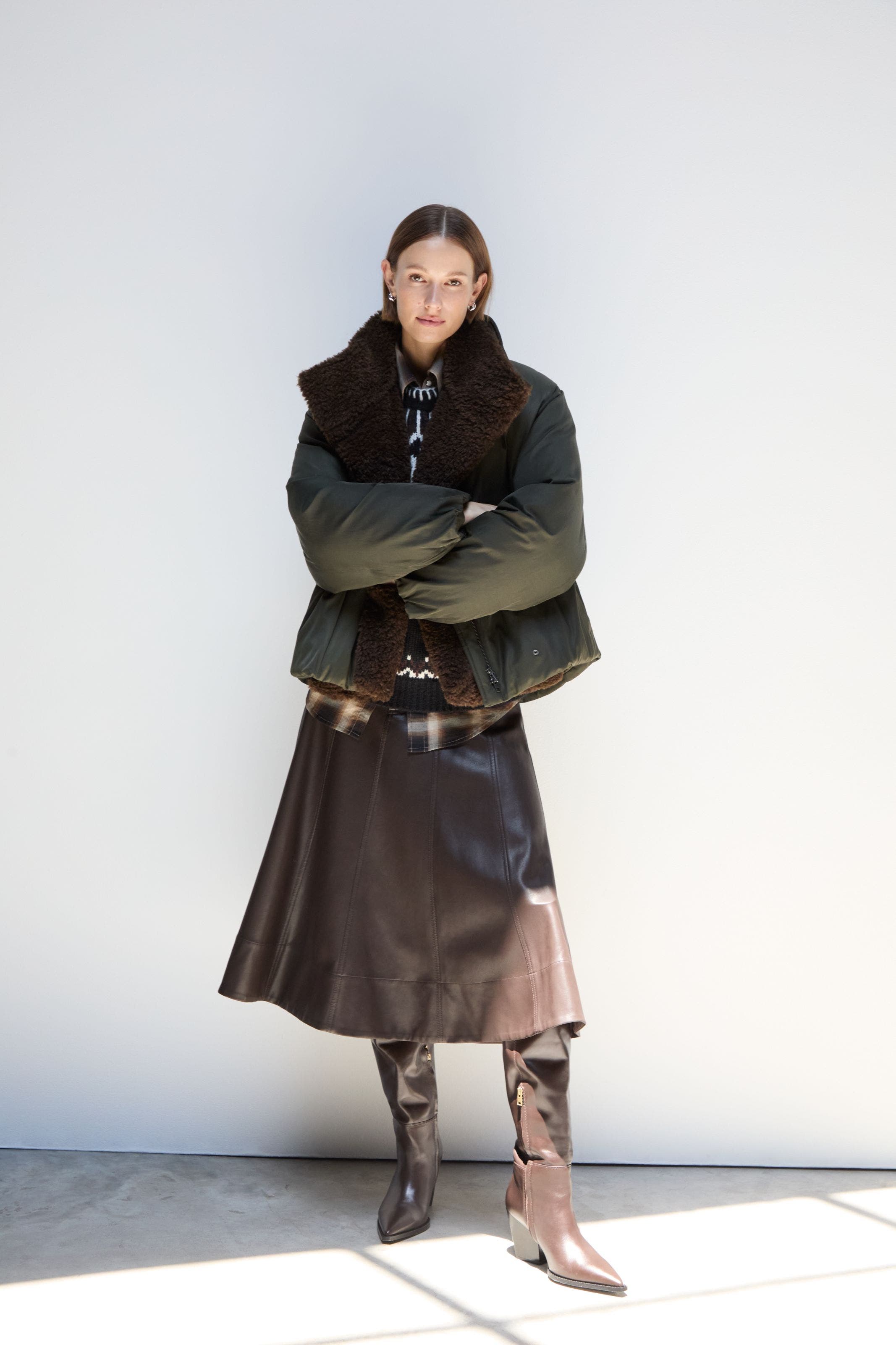A woman wearing a fuzzy vest and skirt.
