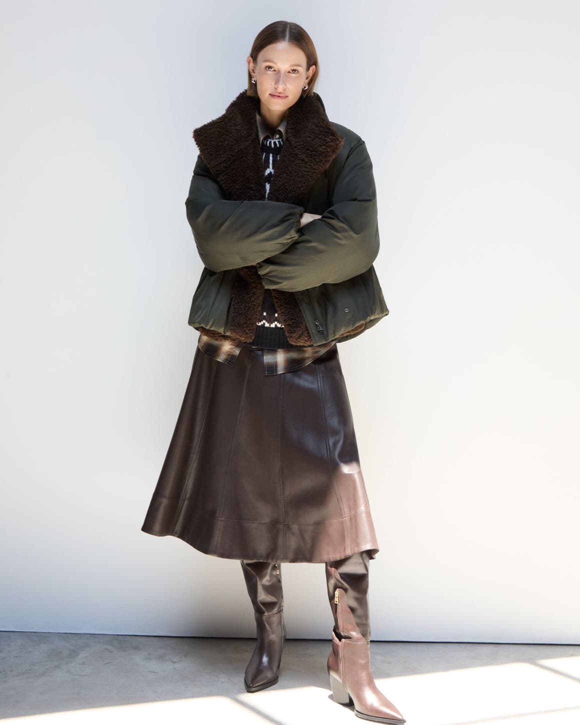 A woman wearing a fuzzy vest and skirt.