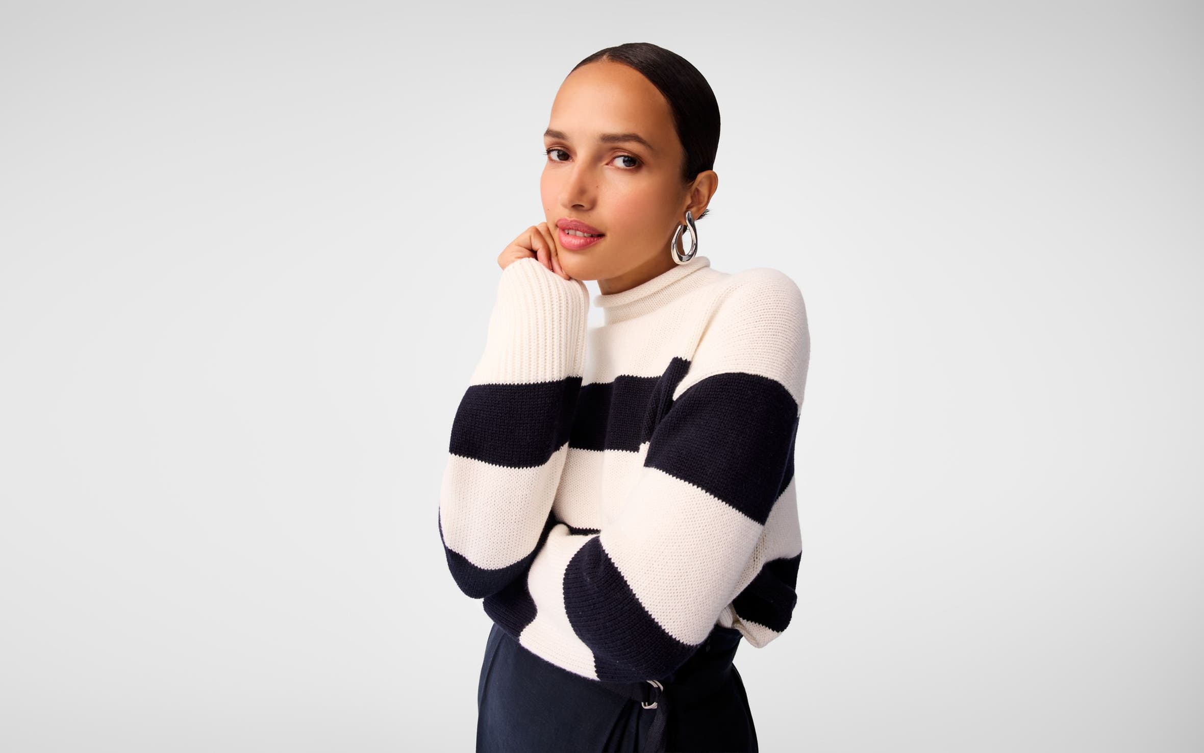 A woman wearing a navy-and-white striped sweater and silver earrings.