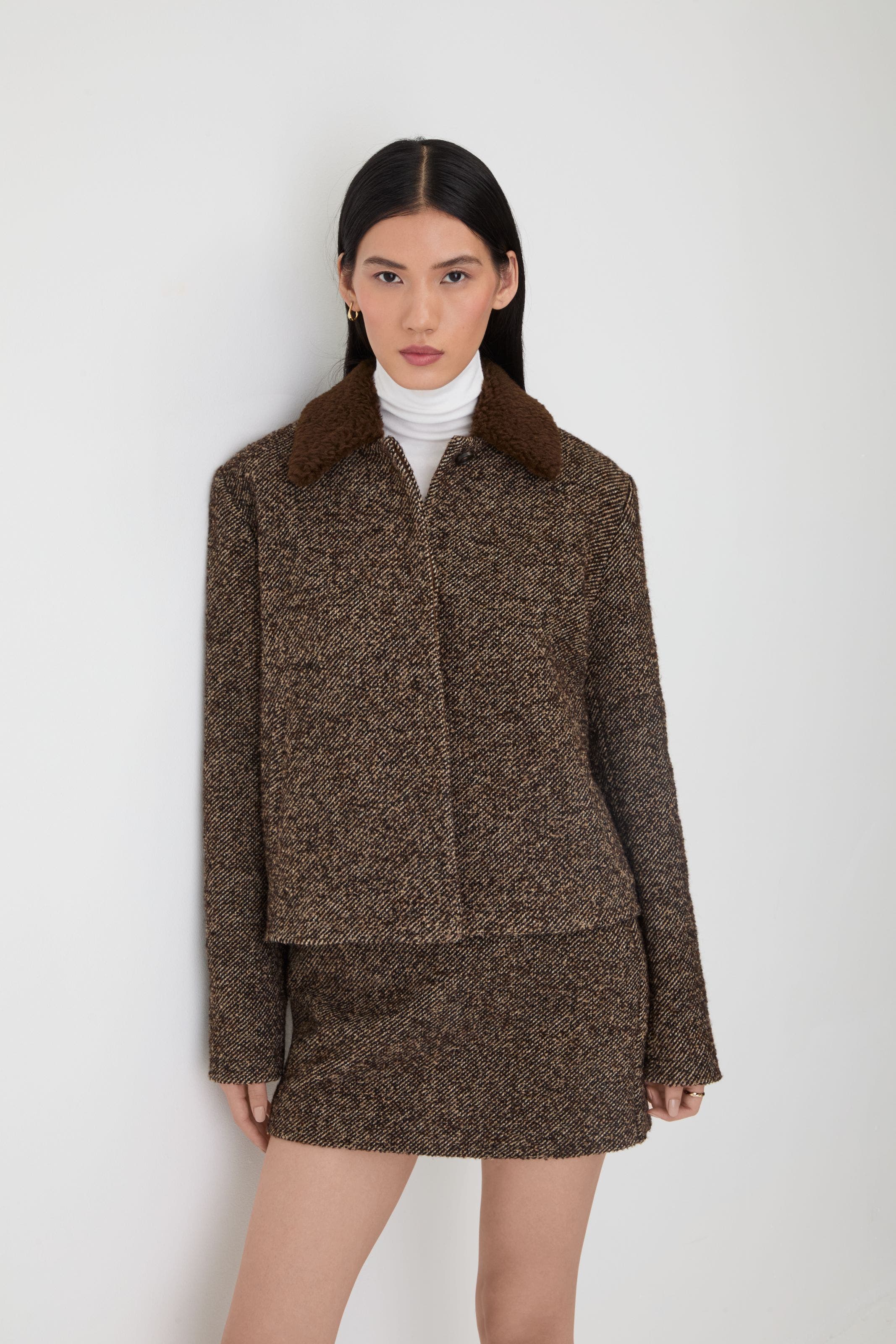 A woman wearing a brown, textured suit.