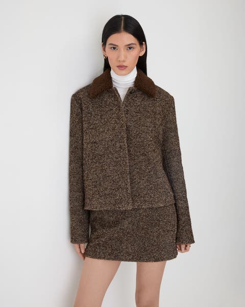 A woman wearing a brown wool jacket and matching mini skirt.