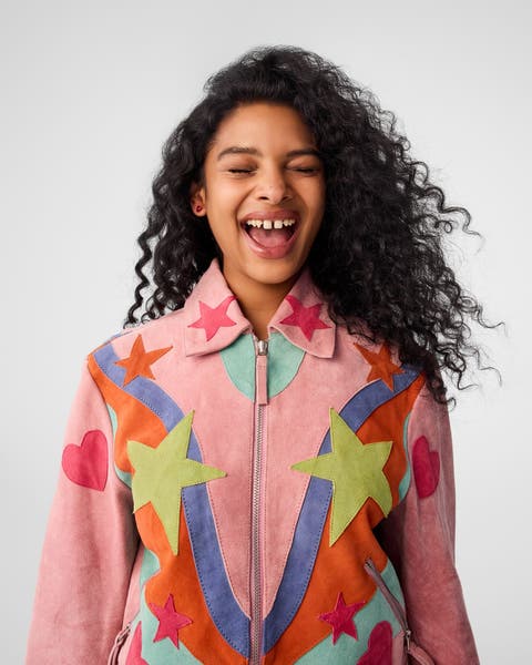 A young woman wearing a pink jacket with colorful stars and hearts on it.