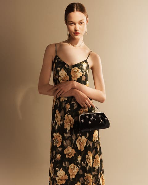 Woman wearing a floral dress and black evening bag.