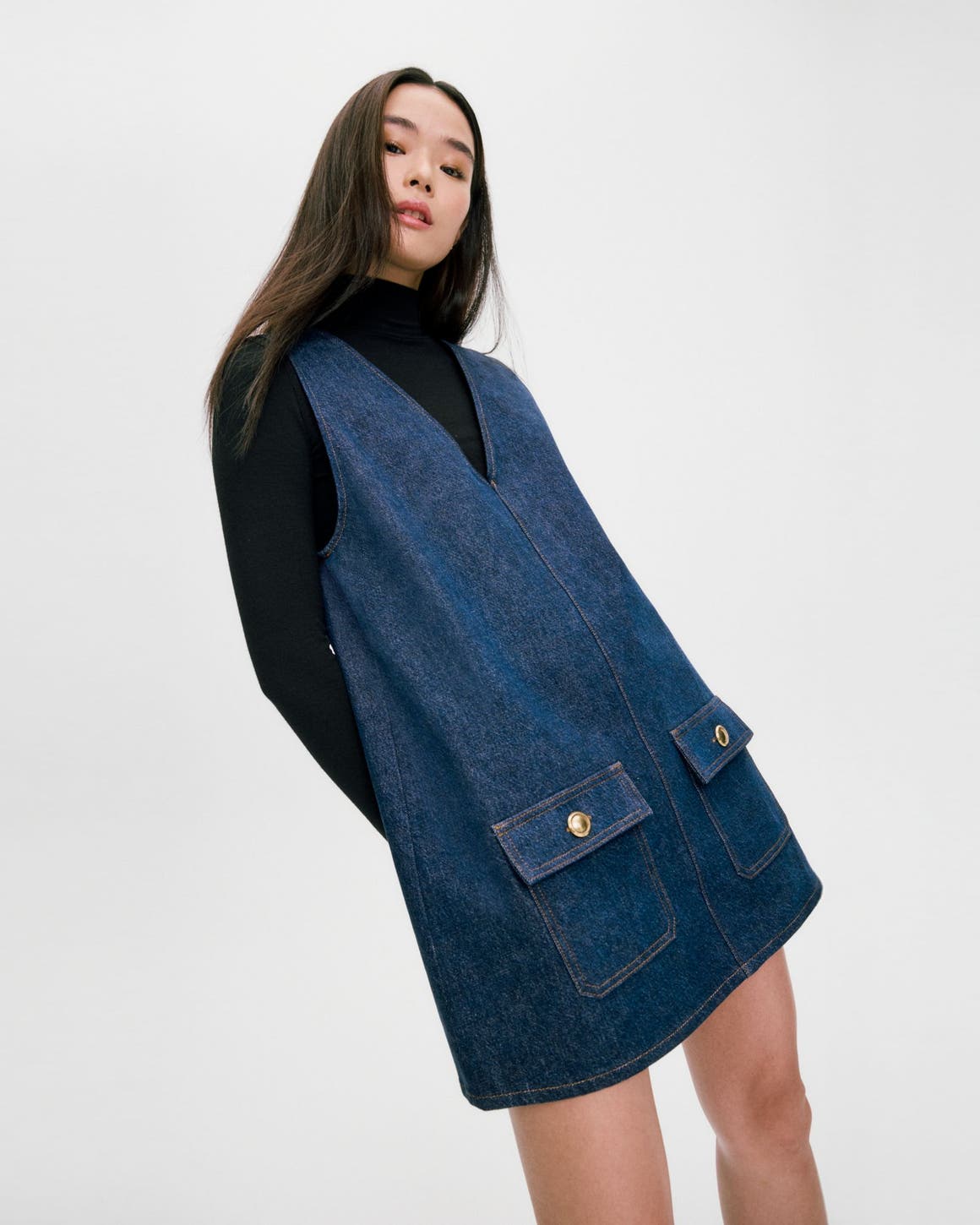 Woman wearing a black turtleneck and blue denim dress.